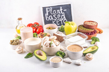 Plant based keto food background with low carb vegan keto diet ingredients, healthy vegetarian fat and protein source. Assortment green vegetables, nuts, legumes, oil, coconut, nuts, peanut butter
