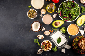 Plant based keto food background with low carb vegan keto diet ingredients, healthy vegetarian fat and protein source. Assortment green vegetables, nuts, legumes, oil, coconut, nuts, peanut butter