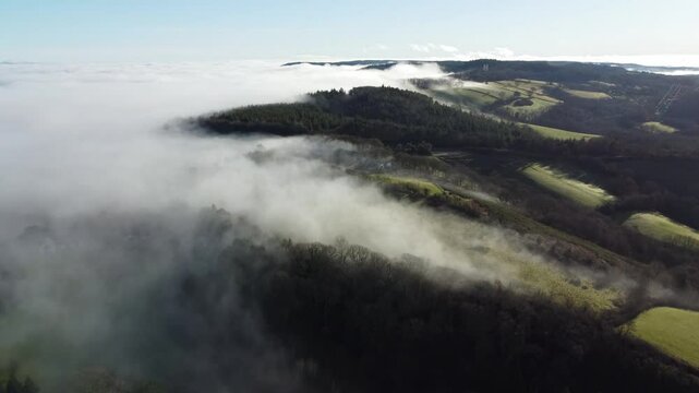 Aerial video of Devon countryside with rolling mist against lush green fields below. Spectacular landscape. 
