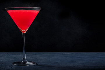Cosmopolitan cocktail with vodka and cranberry juice in an elegant glass, on a black background