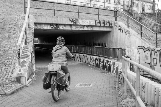 Fototapeta person riding a bicycle in a old abandoned tunnel with graffiti black and white photo