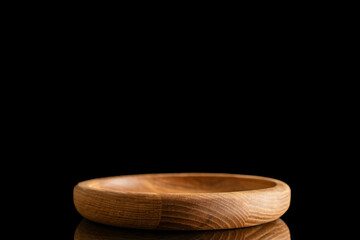 One wooden saucer, close-up, isolated on a black background.