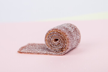 Close-up of a candy roll on pink background.