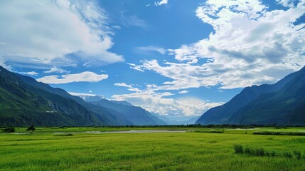 Naklejka premium A beautiful green field with a majestic mountain, a clear river and a vast sky in the background. The idyllic and serene natural scenery creates a peaceful and charming atmosphere.