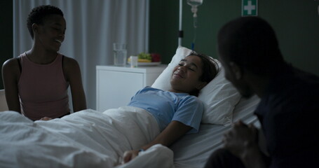 Obraz premium African child is seriously ill in a hospital room with her parents by her side, talking.
