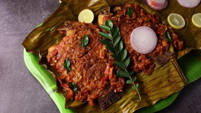Kerala fish curry, Karimeen Pollichathu a popular hot and spicy baked fish in banana leaves Alleppey India. pearl spot fish is marinated with Indian spices then wrapped in plantain leaf and grilled.