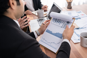 Diverse group of business analyst team analyzing financial data report paper on office table. Chart and graph dashboard by business intelligence analysis for strategic marketing planning Meticulous