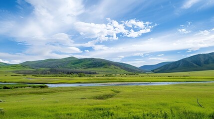 Fototapeta premium A beautiful green field with a majestic mountain, a clear river and a vast sky in the background. The idyllic and serene natural scenery creates a peaceful and charming atmosphere.