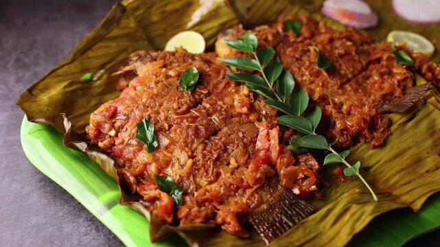 Kerala fish curry, Karimeen Pollichathu a popular hot and spicy baked fish in banana leaves Alleppey India. pearl spot fish is marinated with Indian spices then wrapped in plantain leaf and grilled.