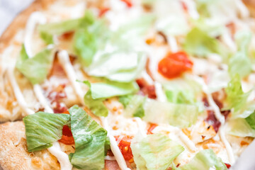 Close-up of Caesar pizza with iceberg leaves, tomatoes and sauce. Concept: fast food, high-carbohydrate food. Consumption of unhealthy food. Eating disorder. Diet. Stick to a healthy diet
