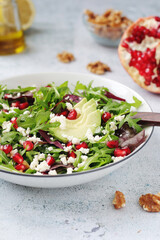 A plate with green rocket salad with pomegranate and avocado	
