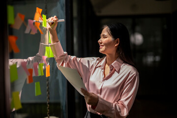 A woman is writing on a white board with colorful markers