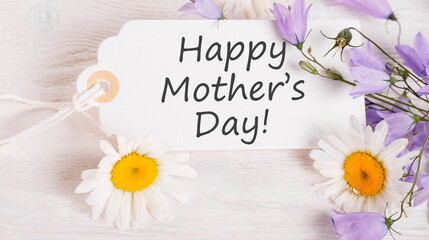 White note with elegant script for Mother's Day surrounded by white daisies and purple flowers, Mother's Day message radiates warmth, white background emphasizes purity, perfect for loving celebration