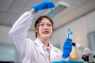 A woman in a lab coat holding a test tube with a blue liquid in it