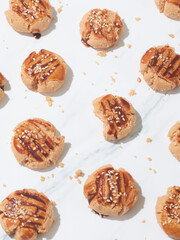 A variety of peanut butter cookies are arranged on a marble surface, some drizzled with chocolate and topped with nuts, showcasing delightful treats