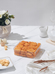 A beautifully arranged table features a tray of golden pastries, a vase with flowers, and elegant glassware in a bright, inviting setting