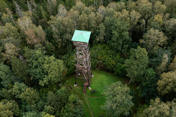 A wooden observation tower stands tall amid lush greenery with overcast skies above.