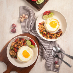 Fresh stir-fried shrimp and vegetables are elegantly presented alongside perfectly cooked eggs and rice, accompanied by sliced cucumbers and tomatoes