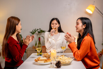 Three women are sitting at a table with wine glasses and food