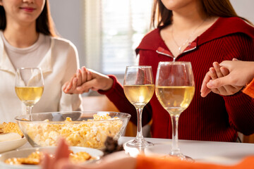 A group of women are gathered around a table with wine glasses and bowls of food