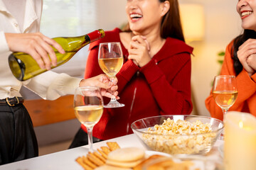 A woman is pouring wine into a glass while two other women are laughing