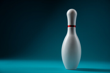 Minimalist photo of bowling pin over dark turquoise blue background. One white bowling pin standing on blue back with copy space.