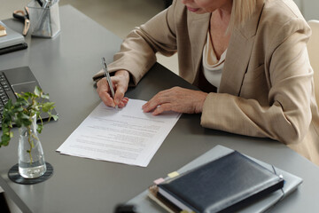 Cropped shot of mature female entrepreneur putting her signature on new business contract after negotiation