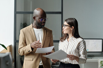Young African American male broker and his female colleague looking at one another during discussion