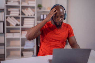 Young african american manager wearing headphones touching his head because of strong headache...