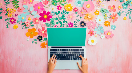 Colorful workspace with laptop surrounded by vibrant paper flowers and creative ambience during daytime hours