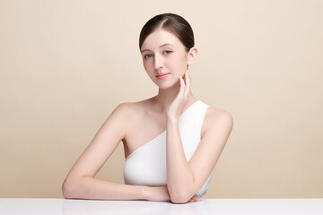 Naklejka premium Beautiful young woman with clean fresh skin on beige background, Face care, Facial treatment, Cosmetology, beauty and spa, women portrait.
