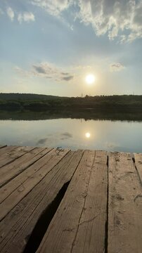 Tranquil sunrise over serene lake with wooden dock and reflective water