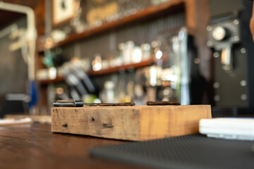 Dried vanilla pods placed on a rustic wooden board in a cozy café setting with blurred background elements.