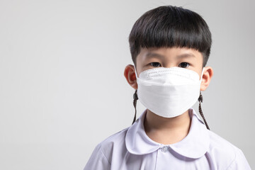 Thai schoolboy wearing a white mask in a studio, looking serious, promoting health and hygiene awareness.