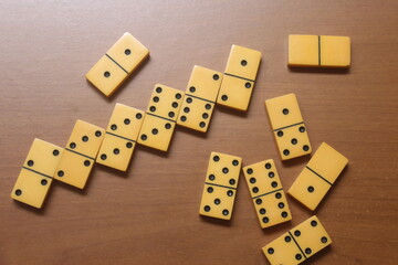 Playing yellow dominoes on a wooden table. Domino effect