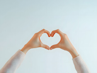Fototapeta premium Hands forming a heart shape, backlit for a soft silhouette effect against a white background