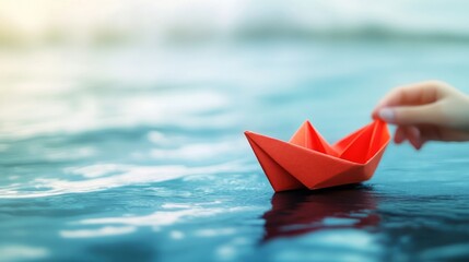 Launching a vibrant red paper boat on a serene paper ocean representing creativity and imagination in a whimsical setting