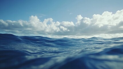 Naklejka premium Calm ocean waves gently rolling under a clear blue sky with fluffy clouds in a serene natural seascape setting