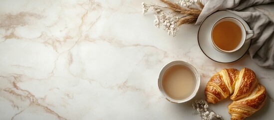 Morning tea and breakfast scene with homemade croissant and beverages on light marble table top view perfect for culinary and lifestyle content