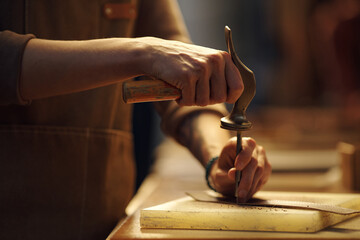 Craftsman working with hand tools in wood workshop, meticulously shaping and sanding wooden pieces....