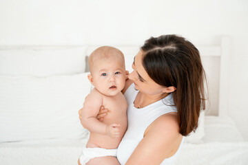 mom with a baby, an international family, a Caucasian mom with an Asian baby in her arms in the bedroom gently hugs him holding him in her arms, a place for text