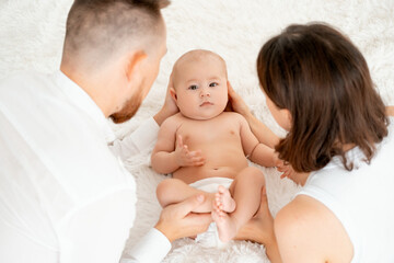 mom, dad with a baby, an international family, a Caucasian mom with an Asian husband and a baby in her arms in the bedroom gently hugs the baby holding in her arms, a place for text