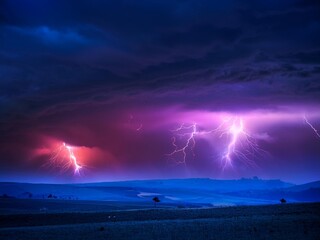 A dark and stormy sky painted in deep purples, blues, and magenta, with swirling clouds illuminated by eerie flashes of lightning. Thick mist rolls over a desolate landscape, creating a dramatic