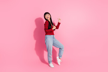 Asian brunette woman wearing casual fashion poses cheerfully in front of a vibrant pink backdrop