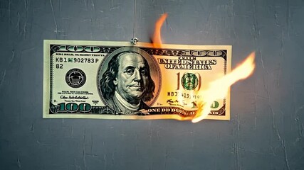 Close-up of a half-burned $100 bill with smoke rising, depicting economic downturn and financial despair