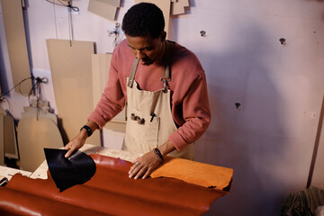 Artisan creating quality leather goods in a well-organized workshop setting, with hands engaged in precise work using high-quality materials and tools