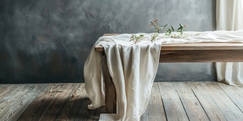 Elegant linen tablecloth on wooden table with a touch of greenery and empty space for text in a stylish, moody interior setting.