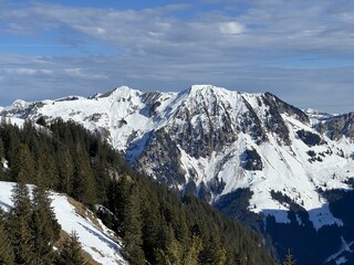 Fototapeta premium Beautiful sunlit and snow-capped alpine peaks above the Swiss tourist sports-recreational winter resort of Engelberg - Canton of Obwalden, Switzerland (Kanton Obwald, Schweiz)