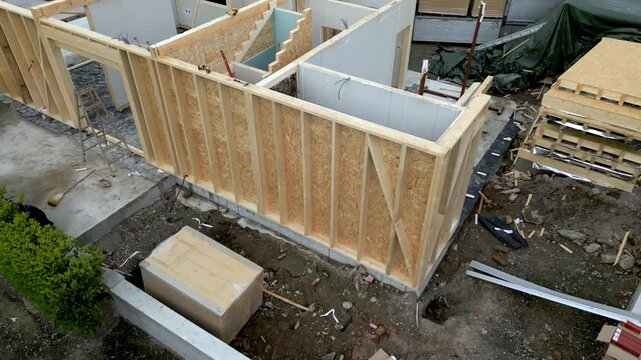 Aerial view of a house under construction with visible wooden framework and structural details. Concept of modern sustainable building methods and urban housing development