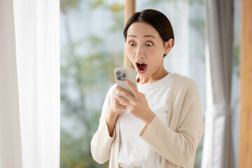 スマホを見ながら驚く女性